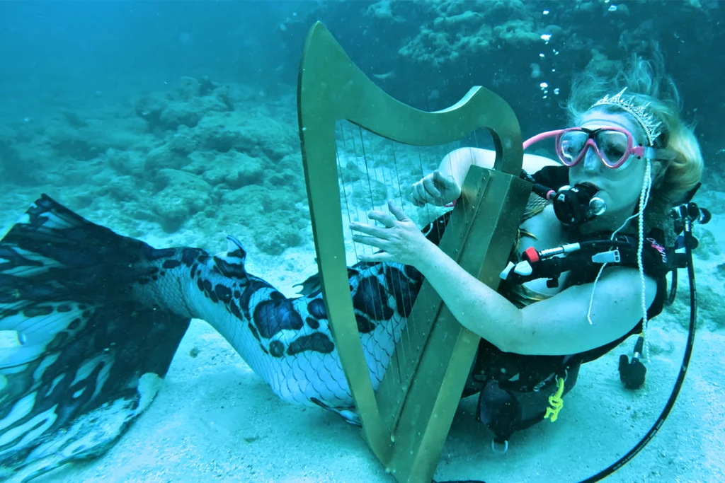 Mermaid plays harp underwater.