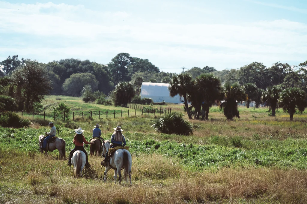 People on horseback ride through SL Brown Ranch