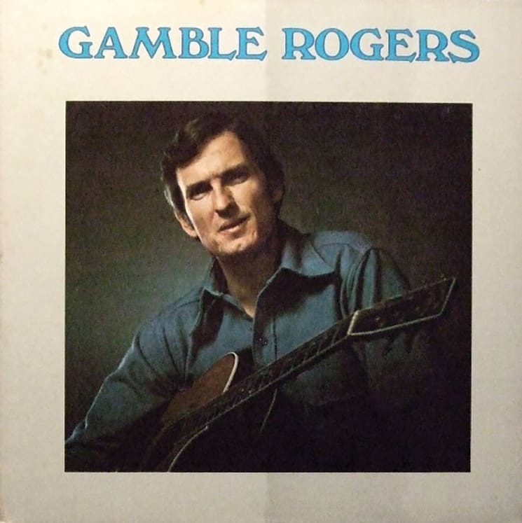 Red, White and JJ GREY 7 A '70s album cover. A neutral backdrop with blue, all-caps text that reads Gamble Rogers across the top. A shadowy, square portrait of the musician holding his guitar is in the center.