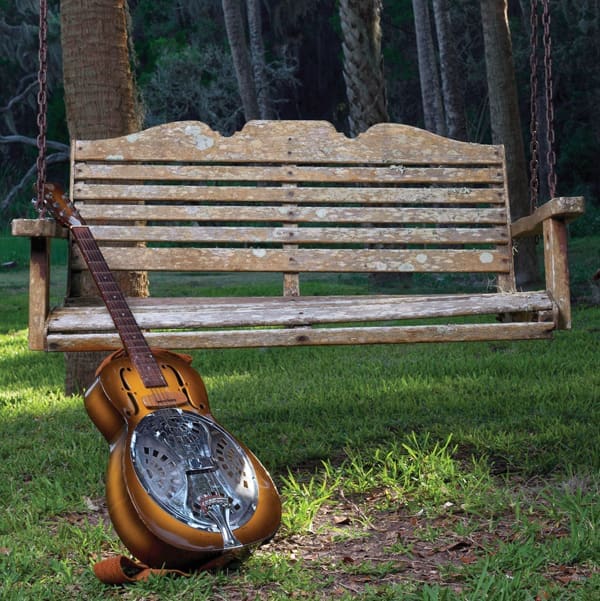 Red, White and JJ GREY 6 JJ Grey's Dobro guitar leans against a wooden tree swing that looks like an old bench.