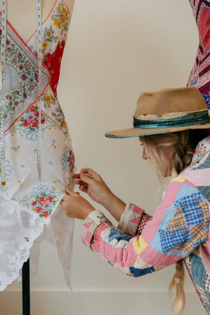 Mary Ellen DiMauro hand stitches a dress made from handkerchiefs.